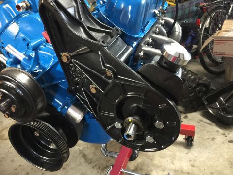 1989 Ford Bronco - Close-up of a blue engine block with a black power steering pump and pulley system installed.