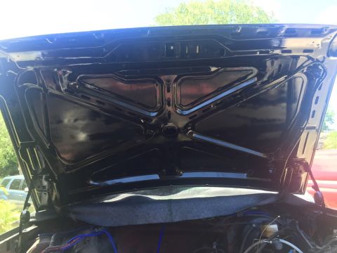 1989 Ford Bronco - The underside of a car's hood is shown, with some engine components visible beneath it.
