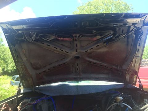 1989 Ford Bronco - The underside of an open hood reveals the engine bay and surrounding components.