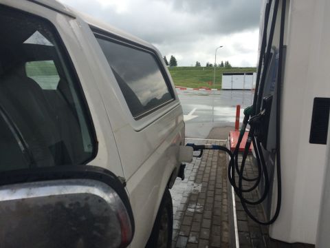 1993 Ford Bronco - A white SUV is parked at a gas pump, with the fuel nozzle inserted into the tank.