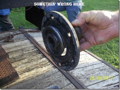 1909 Ford Model T - A hand holds a metal part with bolt holes. Text overlay says 'SOMETHIN' WRONG HERE'.