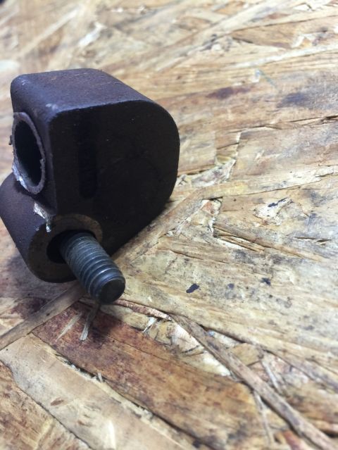 1989 Ford Bronco - Close-up of a metal engine mount bracket with a bolt, placed on a wooden background.