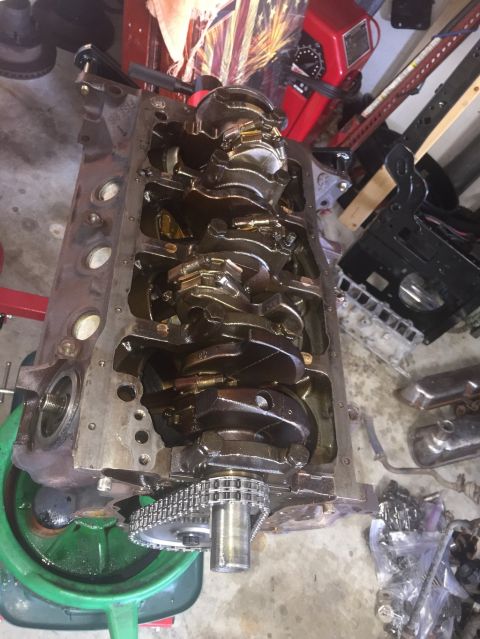 1989 Ford Bronco - Close-up of an engine block's internal components, including the crankshaft and timing chain, with various tools and parts scattered around.