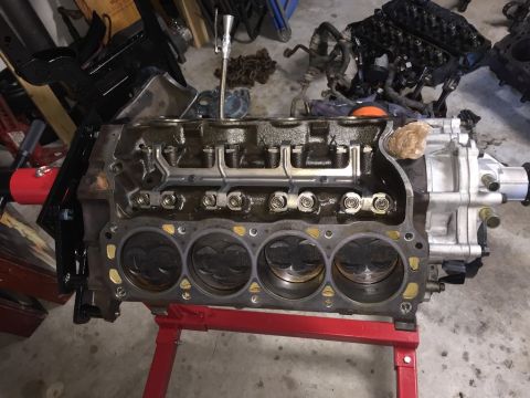 1989 Ford Bronco - Engine block with pistons visible, supported by a red stand. Other engine components are scattered in the background.