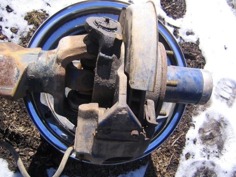 1978 Ford Bronco - Close-up view of a vehicle's axle and brake assembly, a blue hub cap and a shiny rim.
