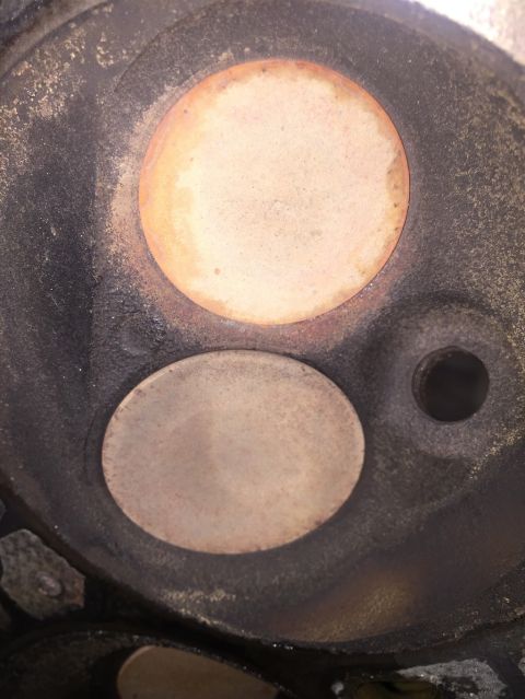 1989 Ford Bronco - Close-up view of an engine cylinder head, revealing two valves and signs of wear and carbon deposits.