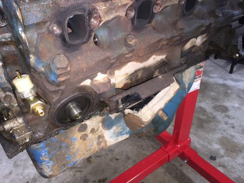 1989 Ford Bronco - Engine block with oil filter housing and sensor, supported by a red engine stand.