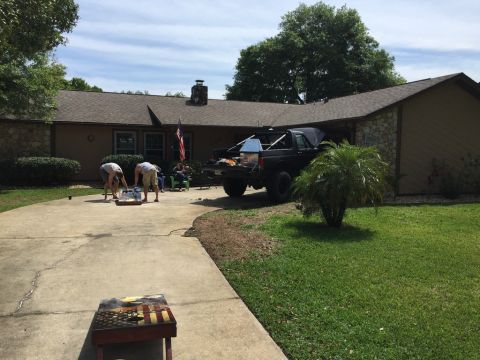 1989 Ford Bronco - A black pickup truck is parked in the driveway of a house, with people playing a yard game.