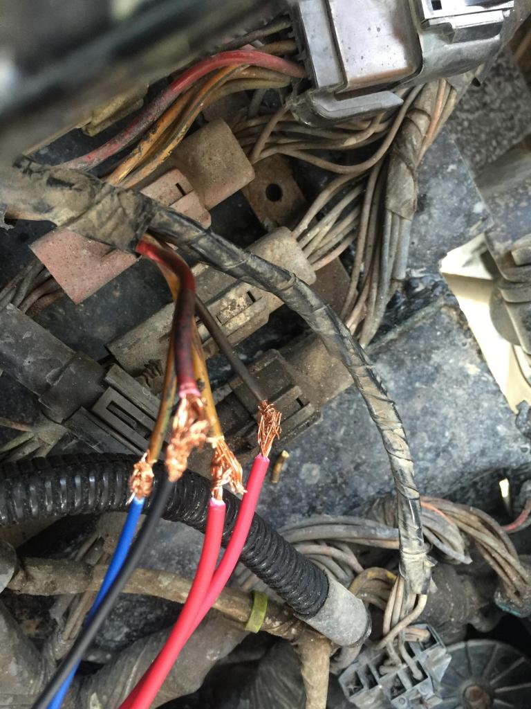 Close-up of frayed wires and connectors in a vehicle's wiring harness