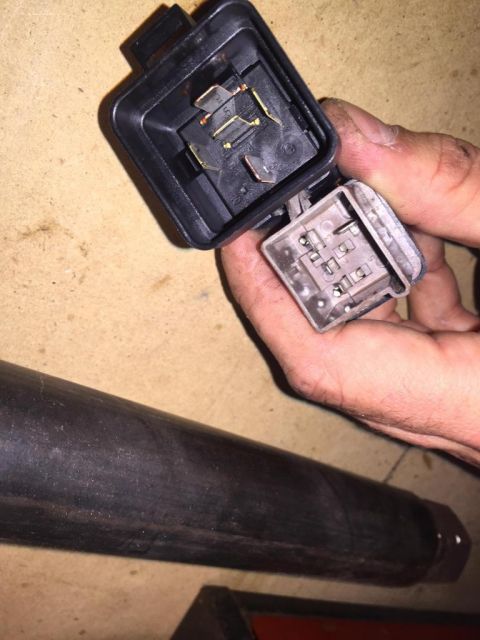 1989 Ford Bronco - A person is holding a car's electrical relay and its socket, likely for replacement or inspection.