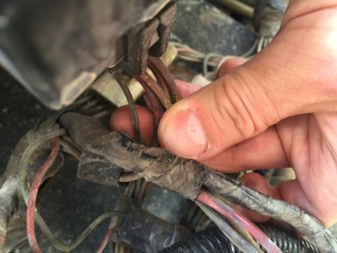 1989 Ford Bronco - A hand works on a complex wiring harness, suggesting a repair or diagnostic process.
