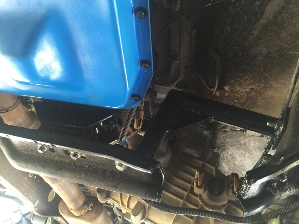 Close-up of a modified transmission crossmember with a blue oil pan visible