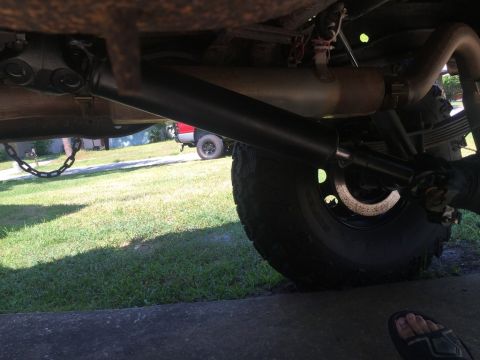 1989 Ford Bronco - Close-up of a vehicle's driveshaft and differential, with another vehicle in the background.