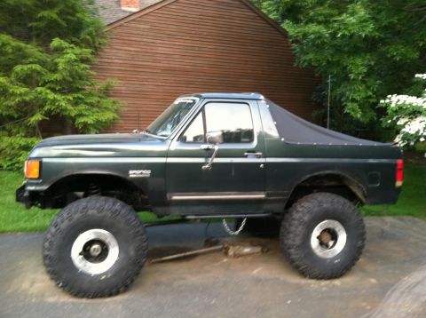 1989 Ford Bronco - This modified Ford Bronco features a soft top and oversized tires, giving it a appearance.