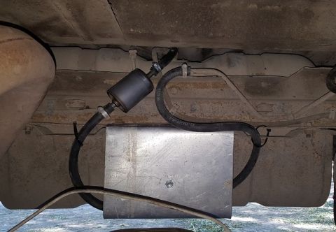 1978 Ford Bronco - The fuel filter and lines are visible along with a metal enclosure on the underside of a vehicle.