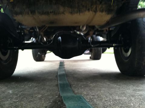 1989 Ford Bronco - Underside view of the rear axle and suspension of a vehicle, likely a truck or SUV, from a low angle. The differential housing is black and…