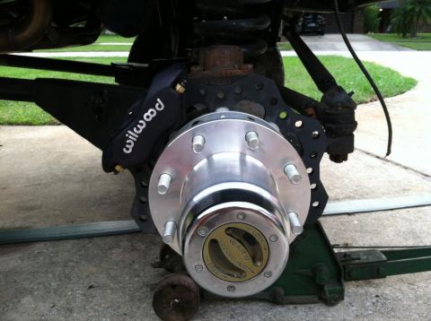 1989 Ford Bronco - A close-up view of the front wheel assembly of a vehicle, featuring a black Wilwood brake caliper and a polished metal hub with a Warn lock…