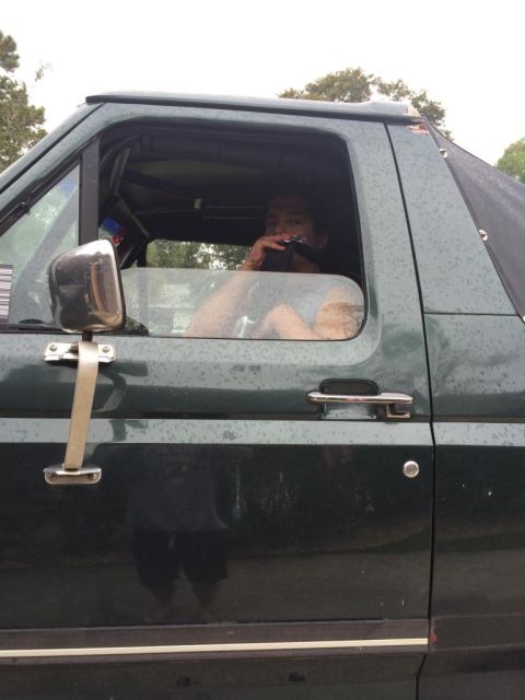 1989 Ford Bronco - A person is visible through the driver's side window of a dark green SUV, holding a black object to their face. The vehicle appears to be a…