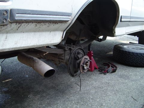 1989 Ford Bronco - The rear axle and suspension components of a vehicle are visible as the wheel has been removed for service.