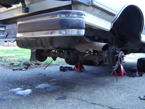 1989 Ford Bronco - The rear axle of a 1989 Ford Bronco is elevated on jack stands for maintenance, revealing the brake system and exhaust.