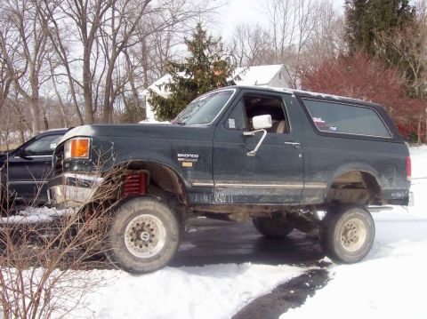 1989 Ford Bronco - A lifted 1989 Ford Bronco sits in a snowy driveway during winter.