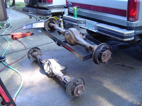 1989 Ford Bronco - Two vehicle rear axles are shown, one on a trailer and the other on the ground, with a truck in the background.