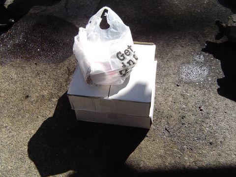 1989 Ford Bronco - A plastic bag with text sits atop two cardboard boxes on a rough surface.