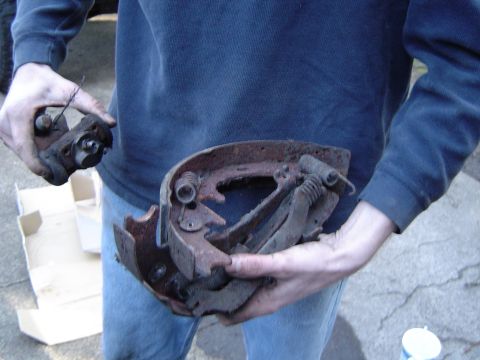 1989 Ford Bronco - Rusty brake drum and caliper assembly held by a person.