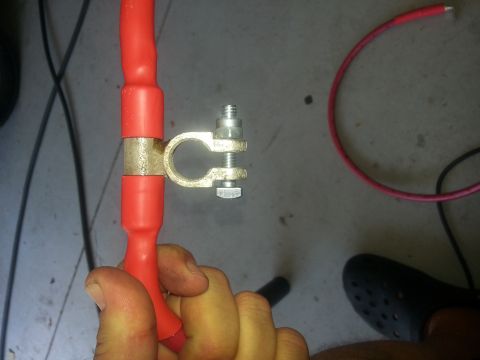 1994 Ford Bronco - Photograph of a red battery cable fitted with a brass post terminal clamp, not a diagram.