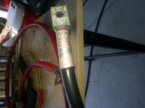 1994 Ford Bronco - Photograph of a battery cable terminal lug bolted to a metal panel with wiring, not a document.