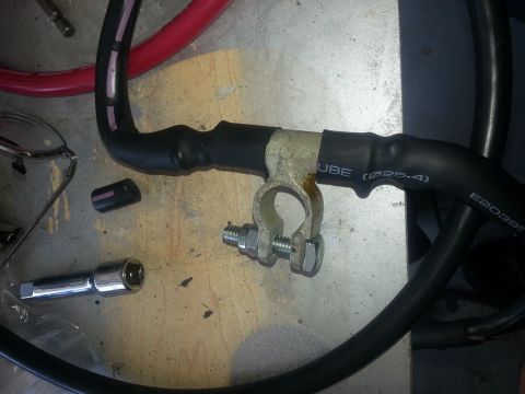 1994 Ford Bronco - Photograph of a fabricated black battery cable with brass terminal on a bench, not a technical document.