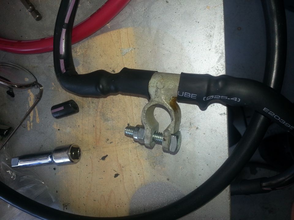 Black battery cable with brass terminal clamp on a workbench