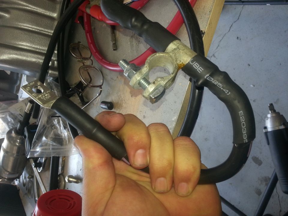 Hand holding black and red battery cables with terminal clamp