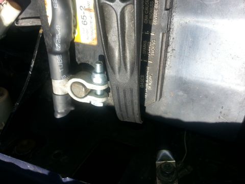 1994 Ford Bronco - Photograph of a battery cable clamp on an installed battery showing the printed warning label, not a data plate.