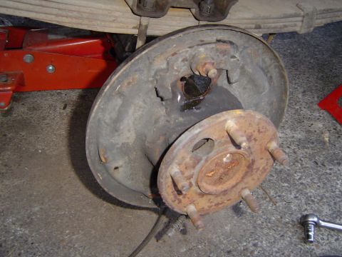 1989 Ford Bronco - A vehicle's rear drum brake assembly is shown, with a red jack and tools nearby.
