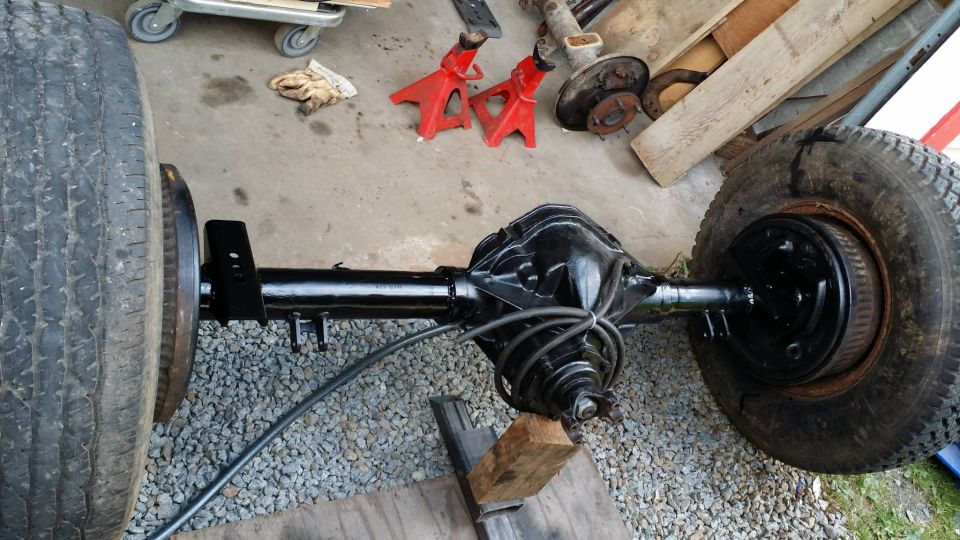 1984 Ford Bronco rear axle assembly with tires and brake drums
