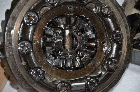 1984 Ford Bronco - A close-up view of a differential assembly, showing gears, bolts, and lubrication. The metal components appear worn and coated in grease.