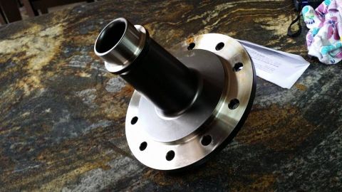 1984 Ford Bronco - A close-up view of a vehicle differential housing with a flange and bolt holes is shown on a granite countertop. The part is dark gray and…