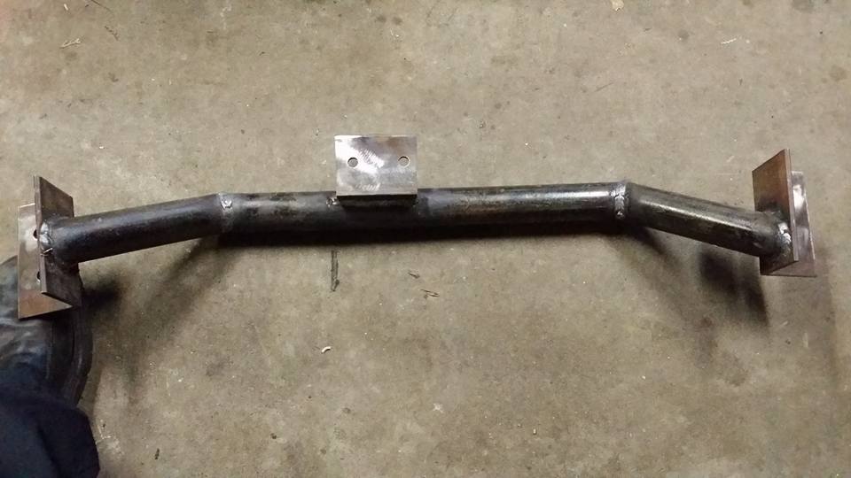 Custom metal crossmember with mounting plates and central bracket on concrete floor