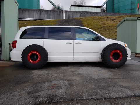 1984 Ford Bronco - A white station wagon with striking red rims is parked outdoors, its side profile clearly visible.