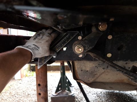 1984 Ford Bronco - Mechanic's gloved hand tightens a bolt on the underside of a vehicle.