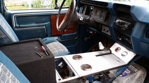 1984 Ford Bronco - The interior of a vehicle shows a custom console and subwoofer box, with a dashboard and steering wheel visible.