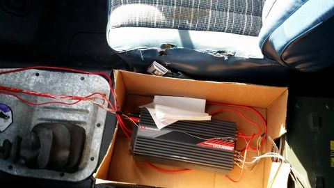 1984 Ford Bronco - Amplifier and wiring are visible inside a vehicle's interior, near damaged seats.
