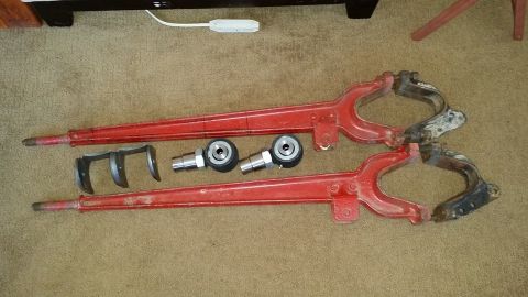 1984 Ford Bronco - Two red control arms and associated hardware are laid out on a carpeted surface.