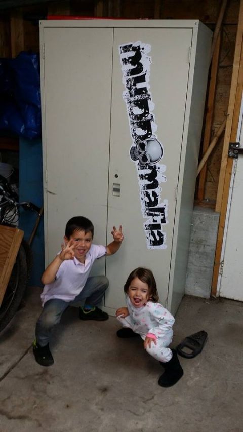 1984 Ford Bronco - Two children are posing in front of a metal cabinet with a sticker on it. The child on the left is making a peace sign with both hands.