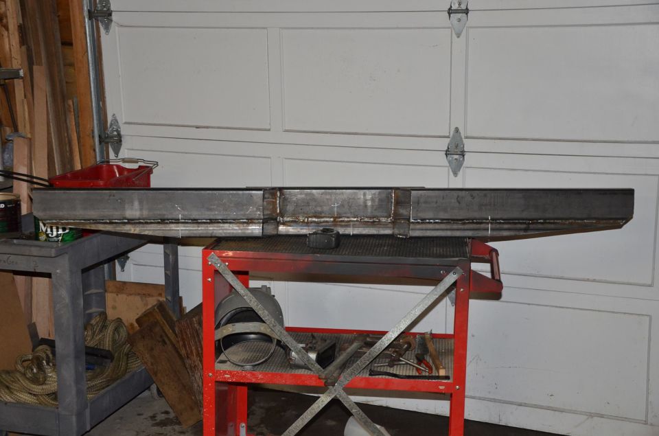 Fabricated metal beam on a red cart in front of a garage door.
