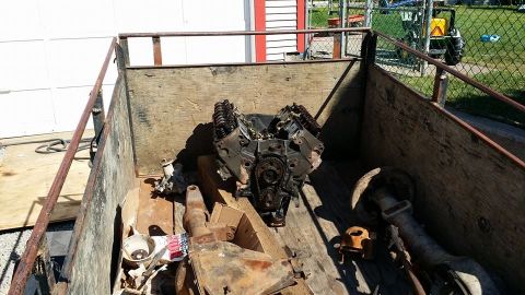 1984 Ford Bronco - A V8 engine, possibly from a Ford Bronco, sits in the bed of a wooden trailer. Various other metal parts and a white funnel are also visibl…
