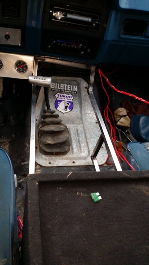 1984 Ford Bronco - Interior view of a vehicle's center console area, showing a gear shifter with a Bilstein and Yukon sticker on the housing. Red wires are vi…