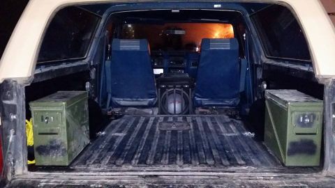 1984 Ford Bronco - The interior of a Ford Bronco is shown from the rear, looking forward. The bed of the vehicle contains two green ammo cans, one on each sid…