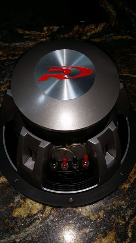 1984 Ford Bronco - A close-up, overhead view of an Alpine subwoofer with a red and silver logo on the dust cap. The subwoofer has a black surround and a silve…